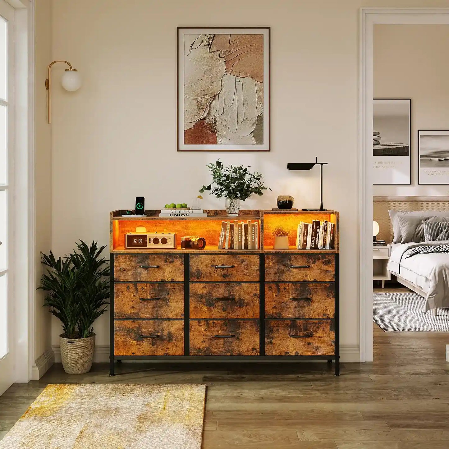A rustic-style wooden sideboard cabinet with distressed orange-brown wood panels and black metal legs, styled in a modern bedroom setting with books, a lamp, and a plant.
