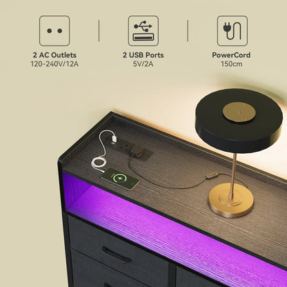 A modern black and gold table lamp sits on a dark wood nightstand with a built-in USB charging port and purple LED under-glow. The image includes feature callout icons at the top describing 2 AC outlets, 2 USB ports, and a 150cm PowerCard.