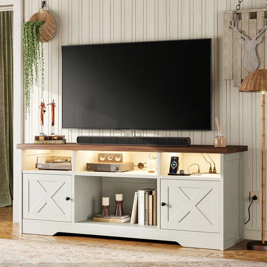 A white TV stand with a dark wood top, featuring two cabinet doors with X-shaped panels, open shelving, and a soundbar and television mounted above on a paneled wall.