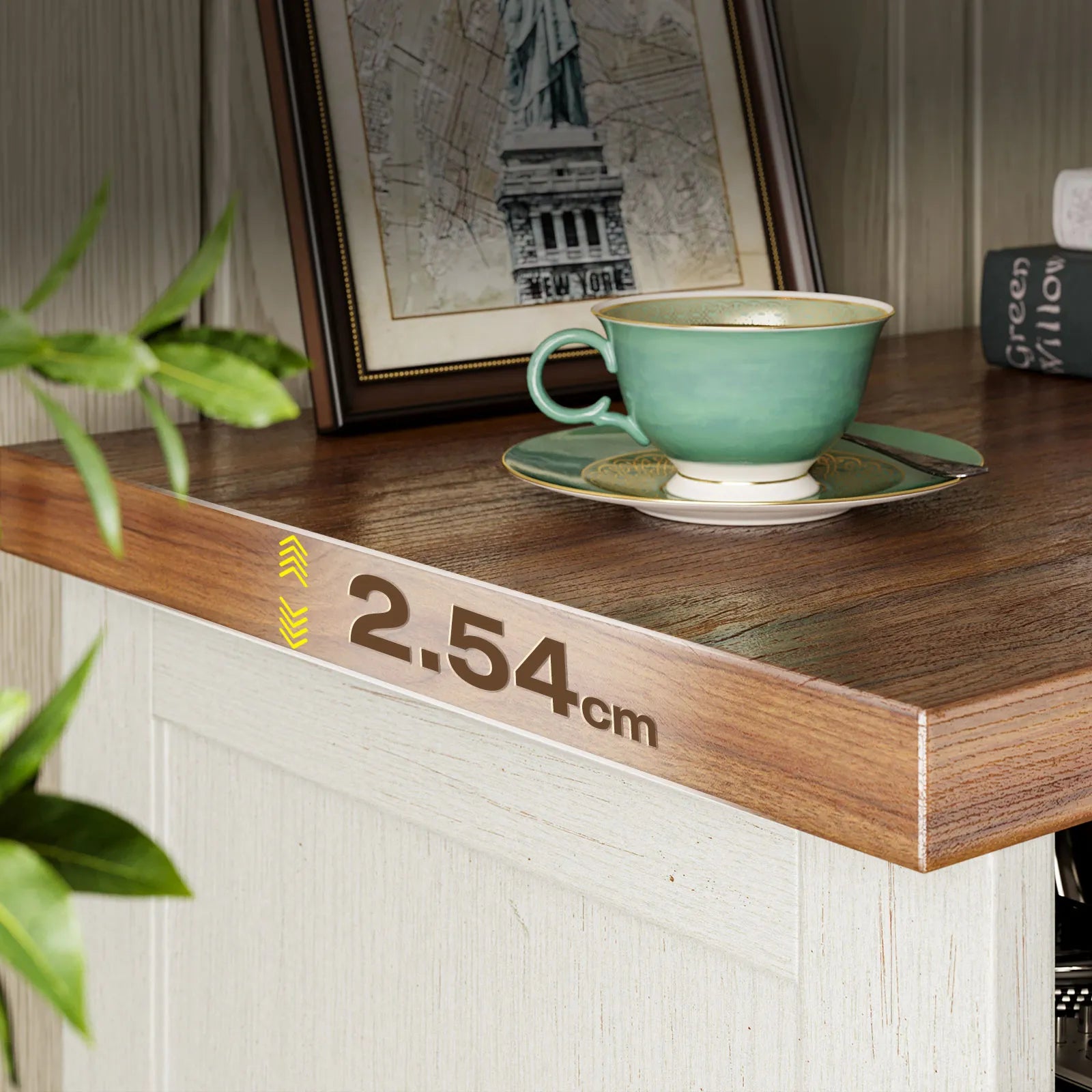 A close-up of a wooden tabletop edge with a printed measurement marking reading 2.54cm, styled with a mint green teacup and saucer, framed art, and a plant in a real interior setting.